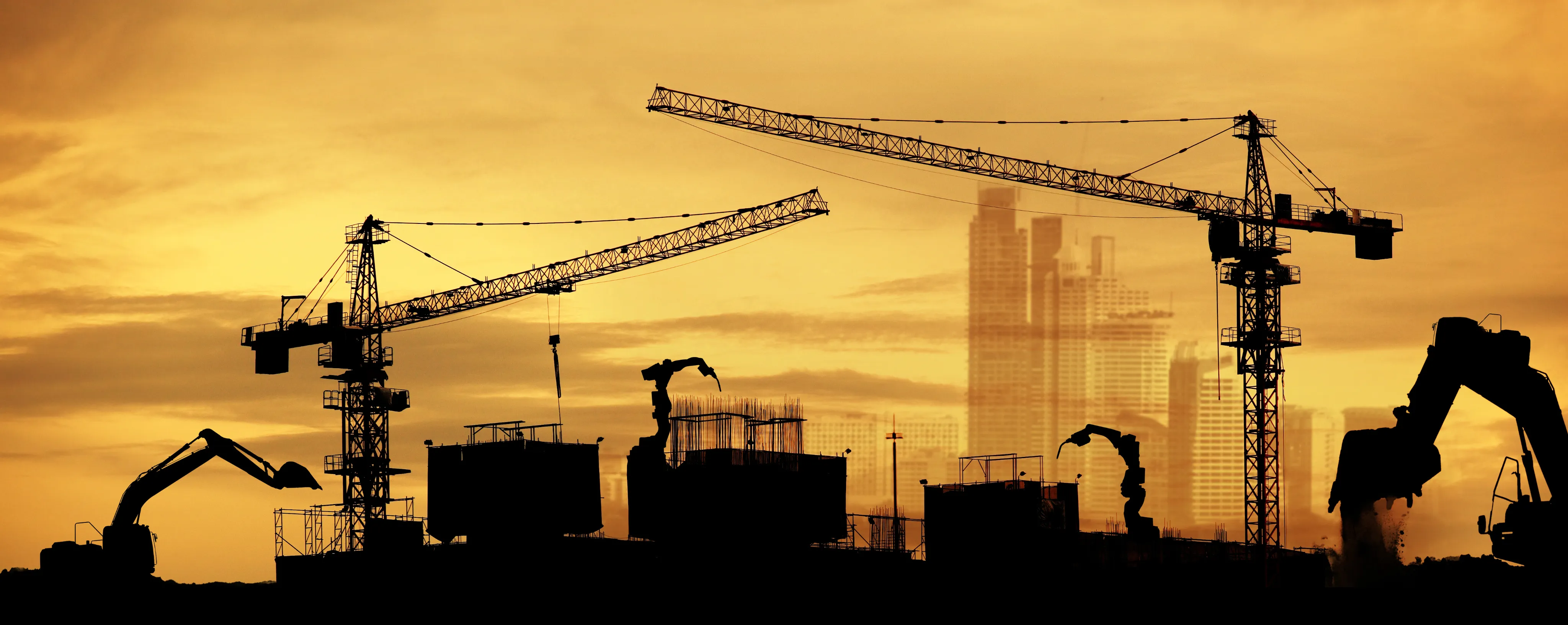 Silhouettes of cranes and excavators at a city construction site during sunset, highlighting heavy equipment use